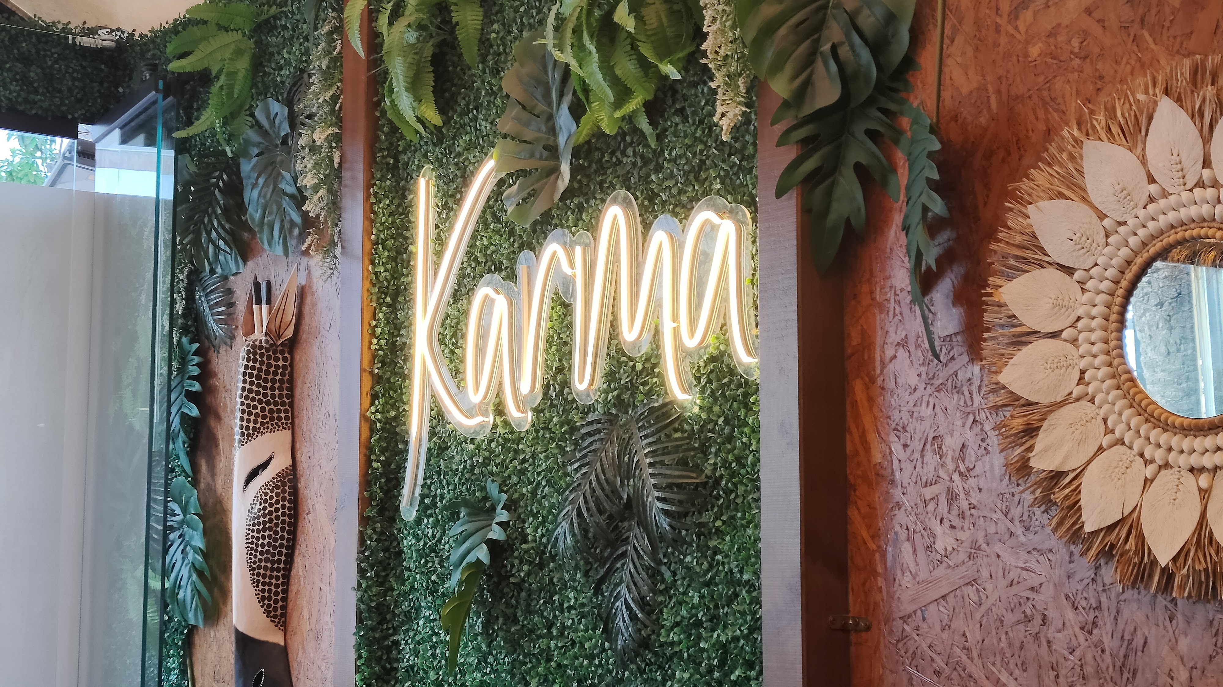 Karma neon sign with green plant wall