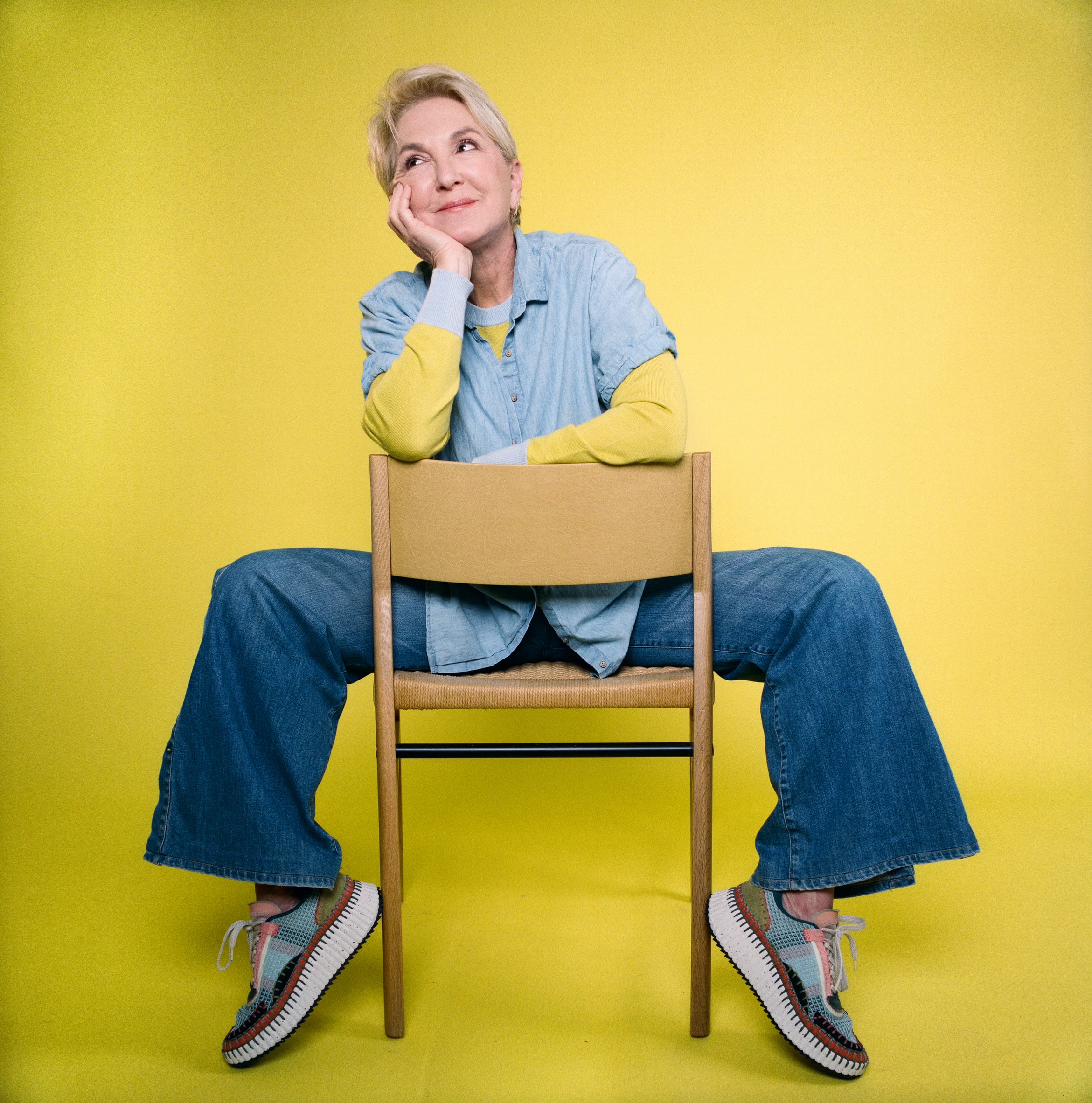 Woman sitting on chair with yellow background