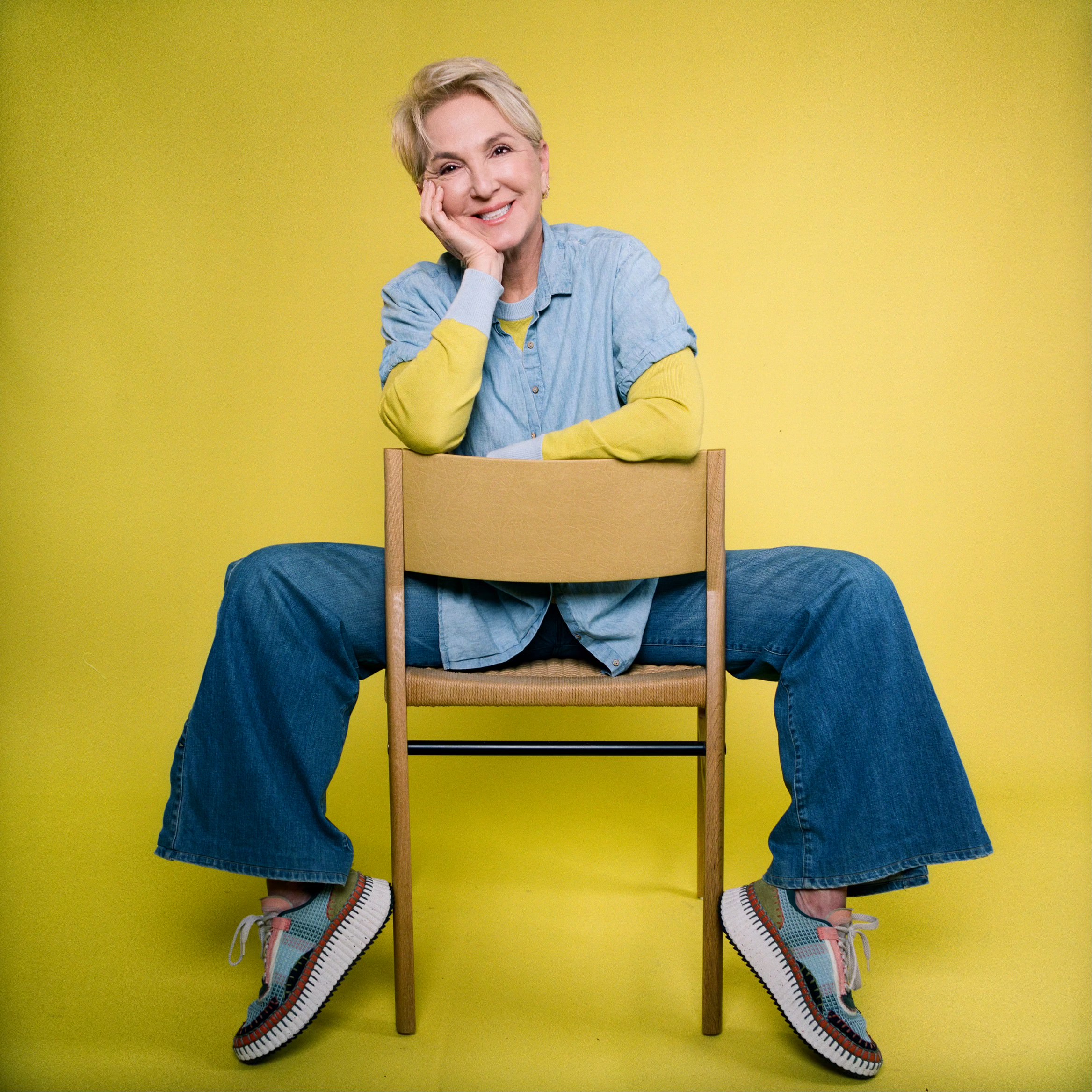 Woman sitting on wooden chair with yellow background