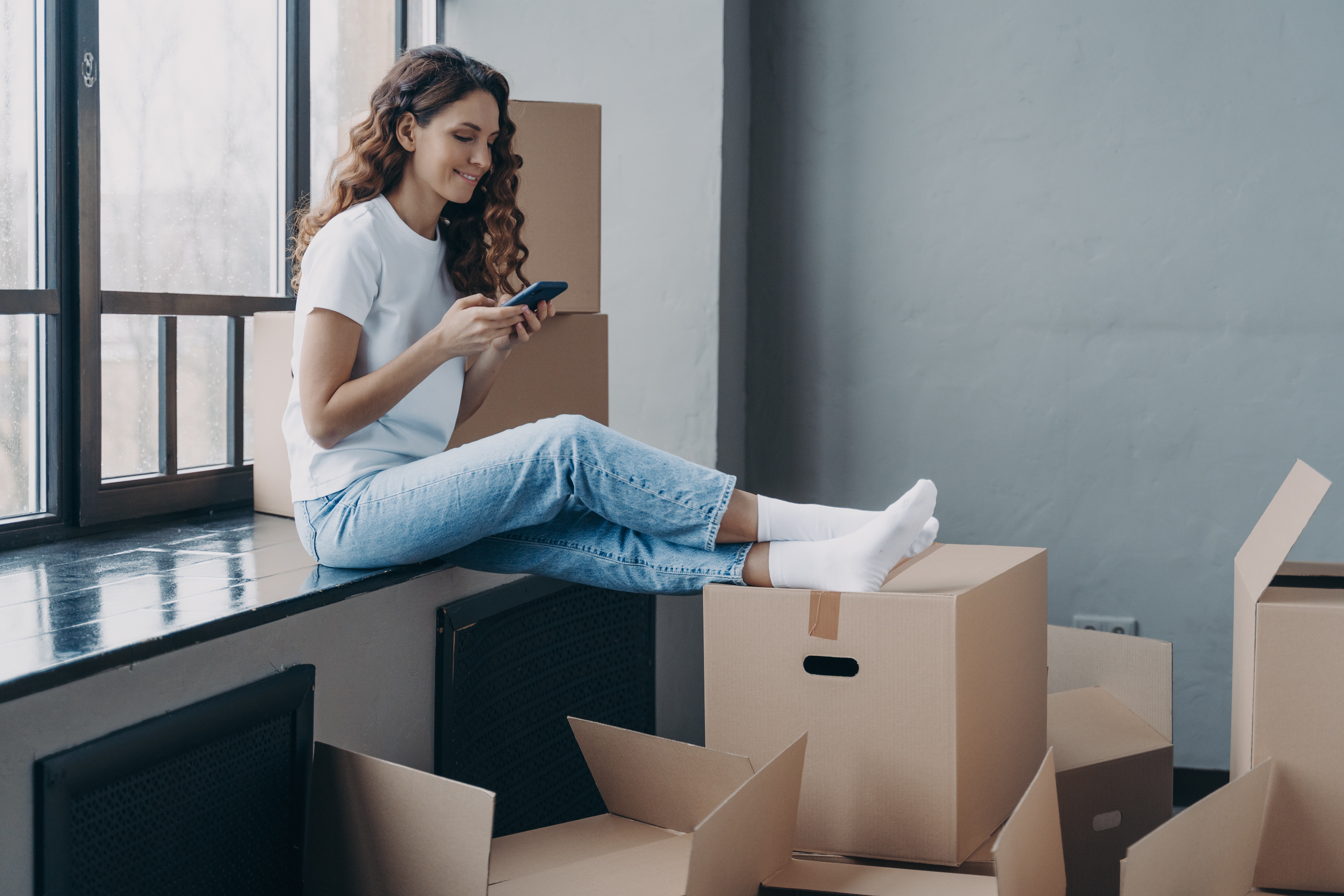 Woman with moving boxes using phone