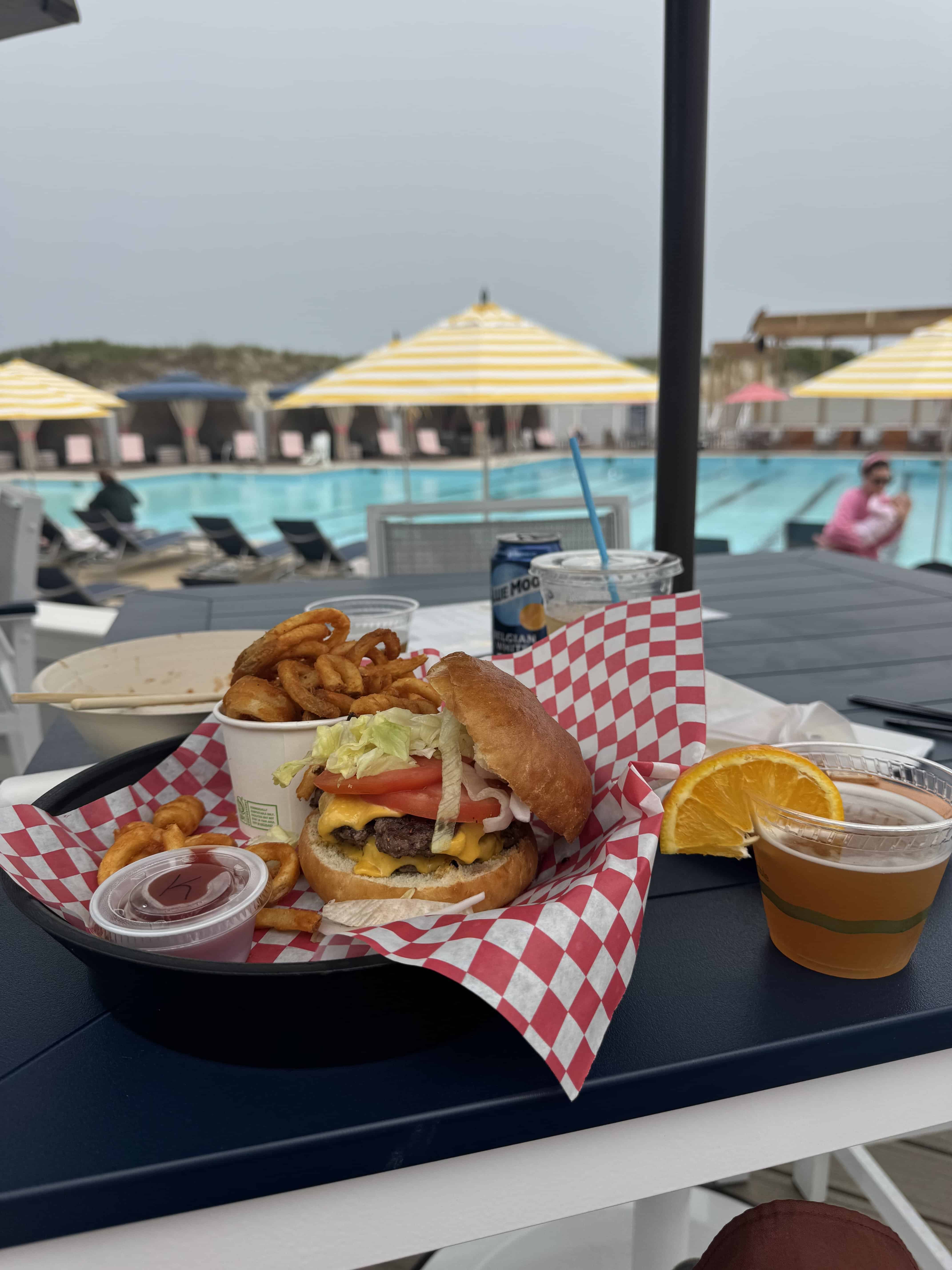 Burger and onion rings with drink poolside